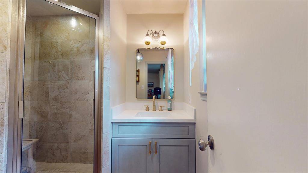 This primary bathroom features a modern design with a glass-enclosed shower, tiled walls, and a sleek vanity with a mirror and elegant lighting.