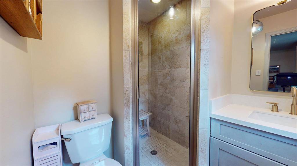 This primary bathroom features a modern shower with tile walls, a sleek vanity with a gold faucet, and a standard toilet. The space is compact yet functional, offering contemporary fixtures and a clean design.