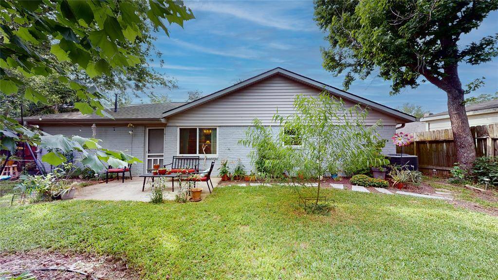 This charming home features a cozy backyard with a lush lawn, mature trees, and a small patio area perfect for outdoor relaxation. The exterior is well-maintained with neutral siding and a welcoming atmosphere.