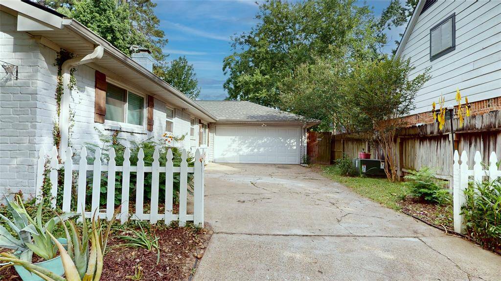 Charming home with a classic white picket fence, lush landscaping, and a spacious driveway leading to a detached garage. Perfect for families seeking a cozy, inviting atmosphere.