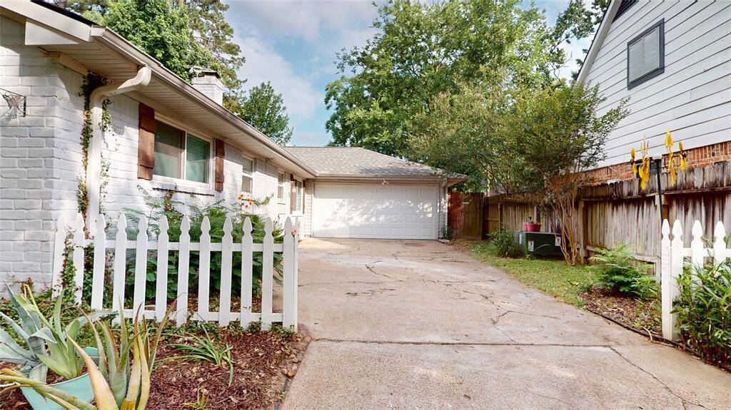 Charming single-story home with a white picket fence, spacious driveway, and attached garage. Features mature trees and cozy landscaping for added privacy and curb appeal.
