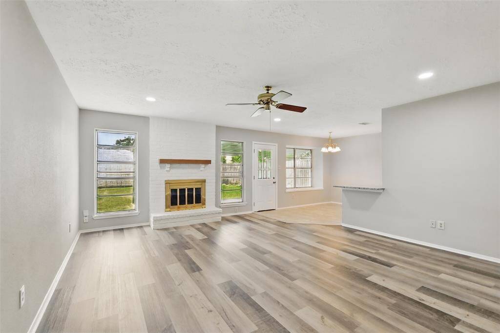 Light and bright living room features energy efficient ceiling fan, wood burning fireplace with mantel, and bar seating adjacent to the breakfast area.