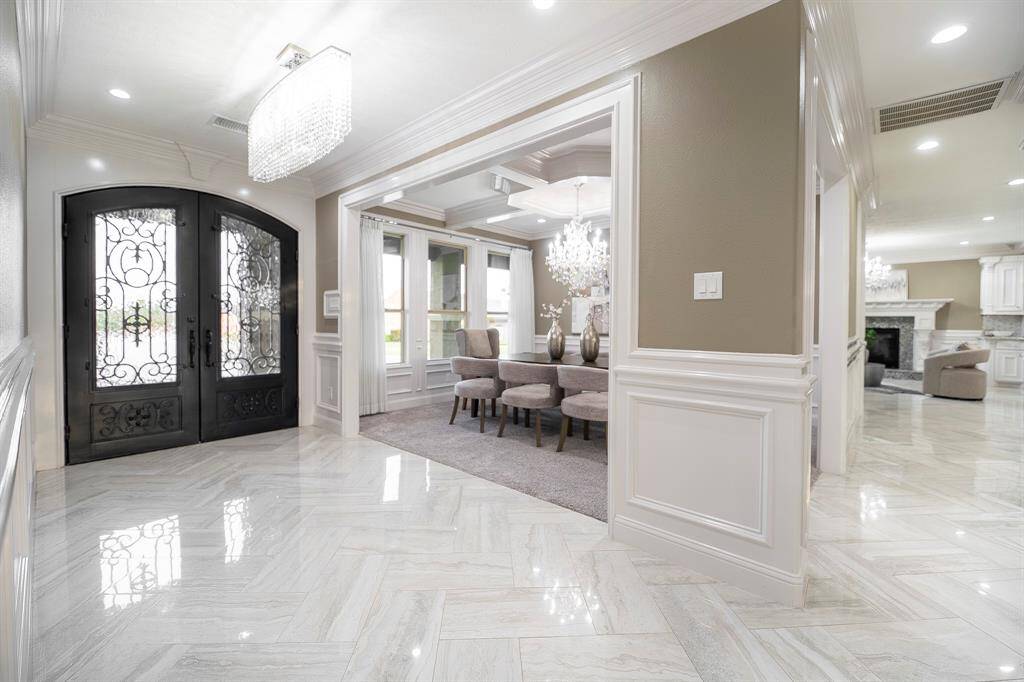 Make a grand first impression in this elegant foyer featuring soaring ceilings, a statement chandelier, and intricate wrought iron double doors that set the tone for the luxury throughout the home.