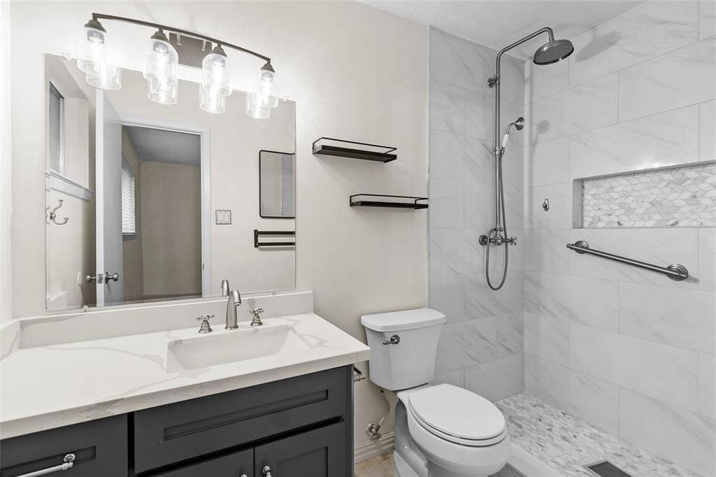 The primary bathroom is equipped with a new walk-in shower, boasting a rain shower head and a stylish shower nook for convenient storage. Modern finishes offer additional storage and an elevated sense of luxury.