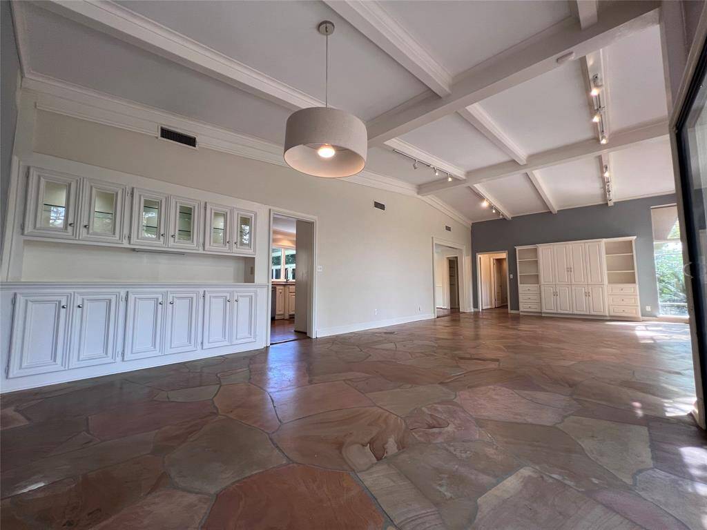 The dining room and den features polished flagstone floors, custom paneled ceiling, built-in buffet with glass front cabinets, mirrored shelves and lighting, and a direct access to the gourmet kitchen.