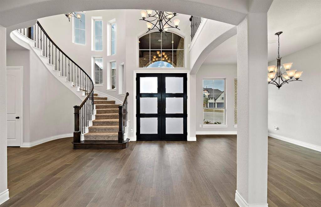 Bathed in natural light from all the tall windows, this open and airy space highlights custom lighting, rich wood floors, and an eye-catching staircase.