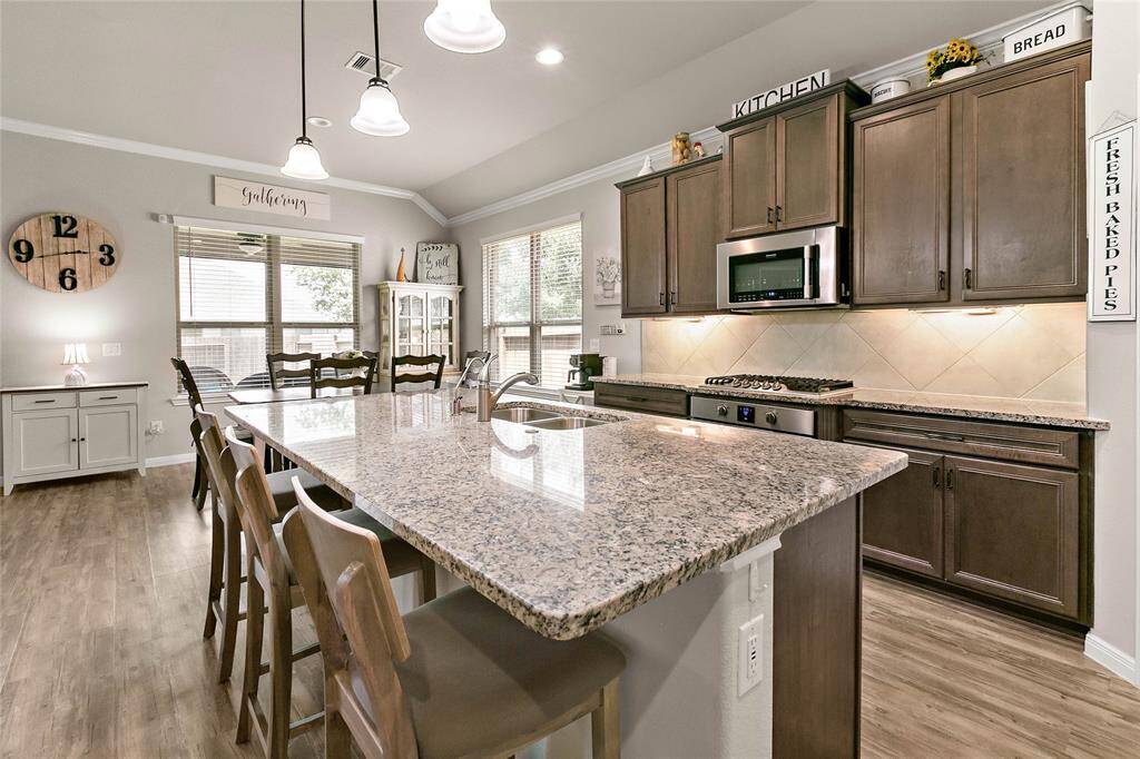The chef's kitchen features a spacious granite island with plenty of bar seating, stainless steel appliances and plenty of storage space.