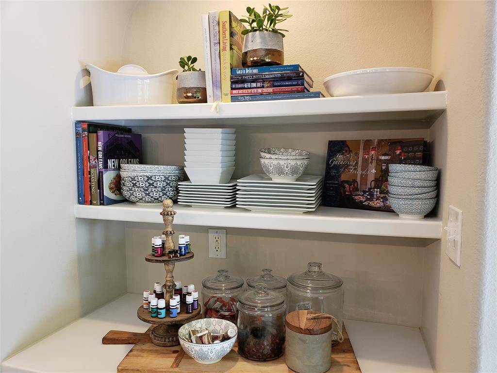 This charming coffee bar nook offers both style and functionality with built-in shelving for cookbooks, dishes, and décor. The spacious counter is perfect for brewing your morning cup, complete with organized storage for essentials and a touch of personal flair.