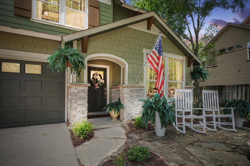 The welcoming front porch exudes charm with classic rocking chairs, lush greenery, and timeless curb appeal—perfect for relaxing and enjoying the quiet cul-de-sac surroundings.
