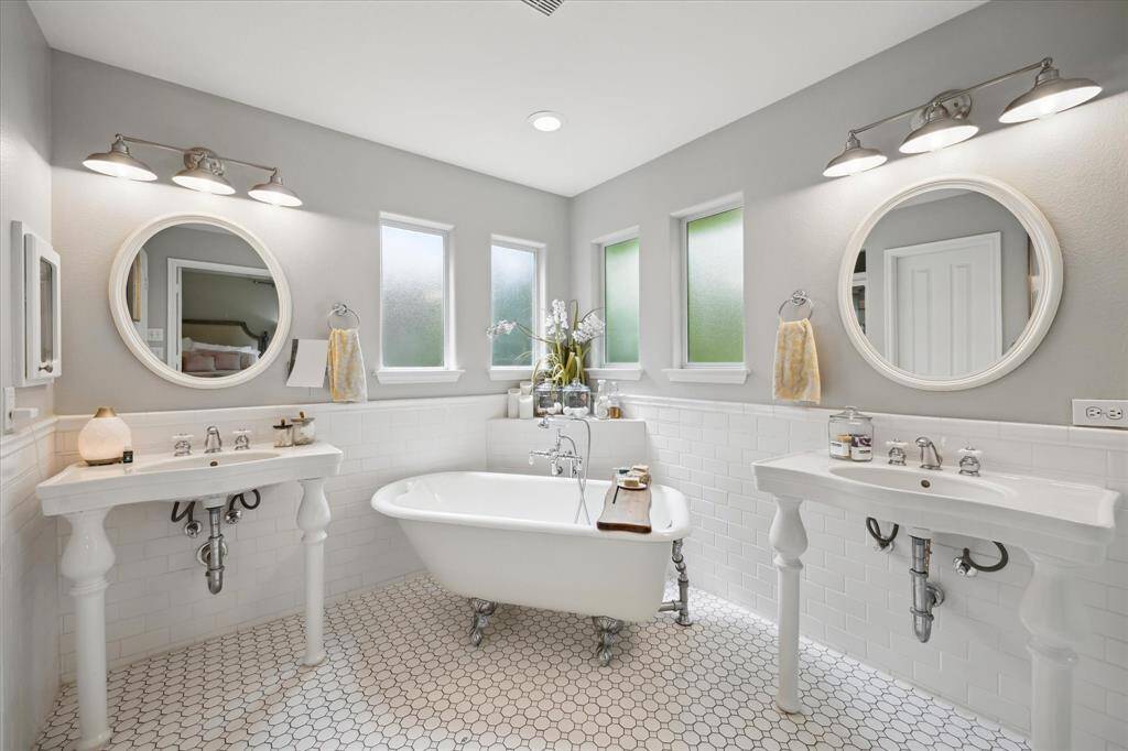 This alternate angle reveals the spa-like ambiance and architectural charm of the primary bath, with soft natural light filtering through frosted windows and a calming palette that enhances the peaceful atmosphere.