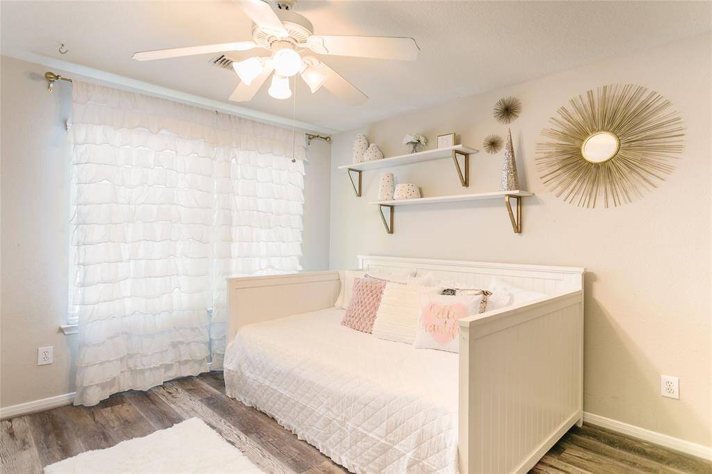 This charming secondary bedroom is filled with natural light and elevated by thoughtful decor elements that enhance both style and function. Floating shelves and whimsical wall art add personality, while built-ins provide practical storage. A soft color palette and layered textures create a cozy, welcoming vibe—perfect for a guest room, nursery, or creative retreat.