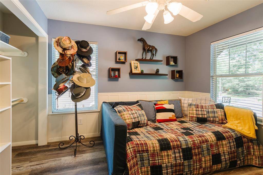 This secondary bedroom offers a cozy, personalized retreat enhanced by classic wainscoting and playful decor. The warm color palette, sports-themed accents, and built-in shelving provide a great example of how thoughtful styling can make a smaller space both inviting and functional—perfect for kids or guests alike.