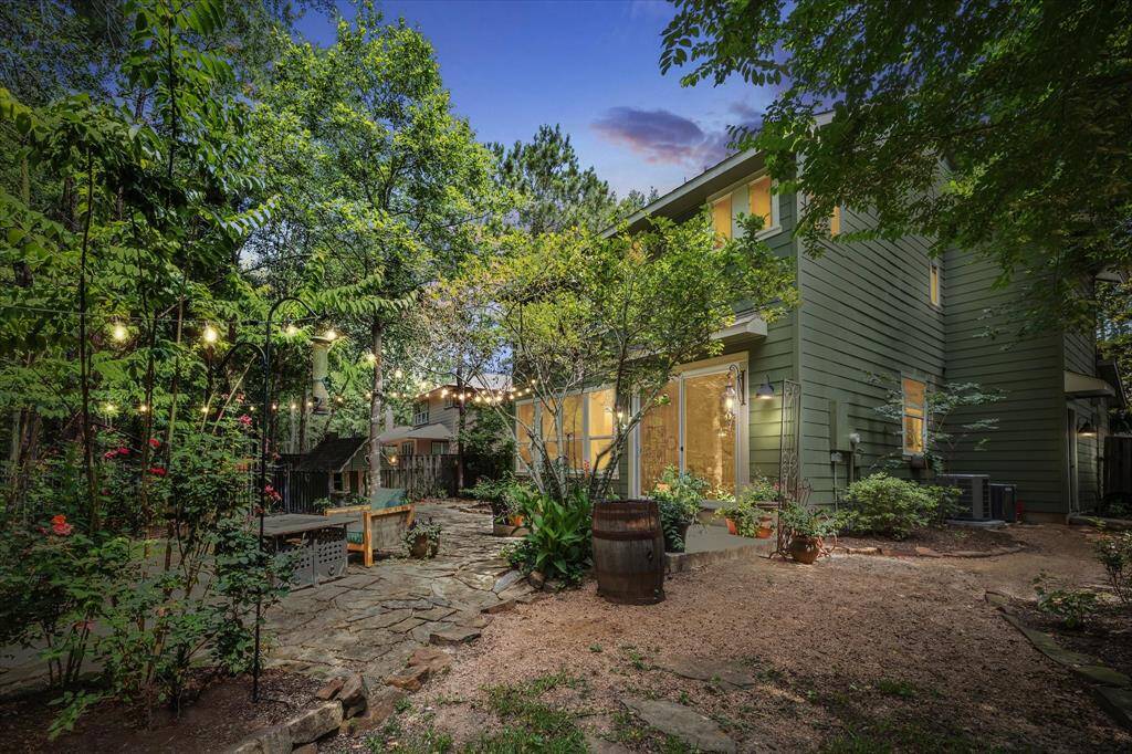 This alternate view highlights the generous side yard and lush natural surroundings, with gravel and stone pathways weaving through established landscaping—offering both functionality and charm.