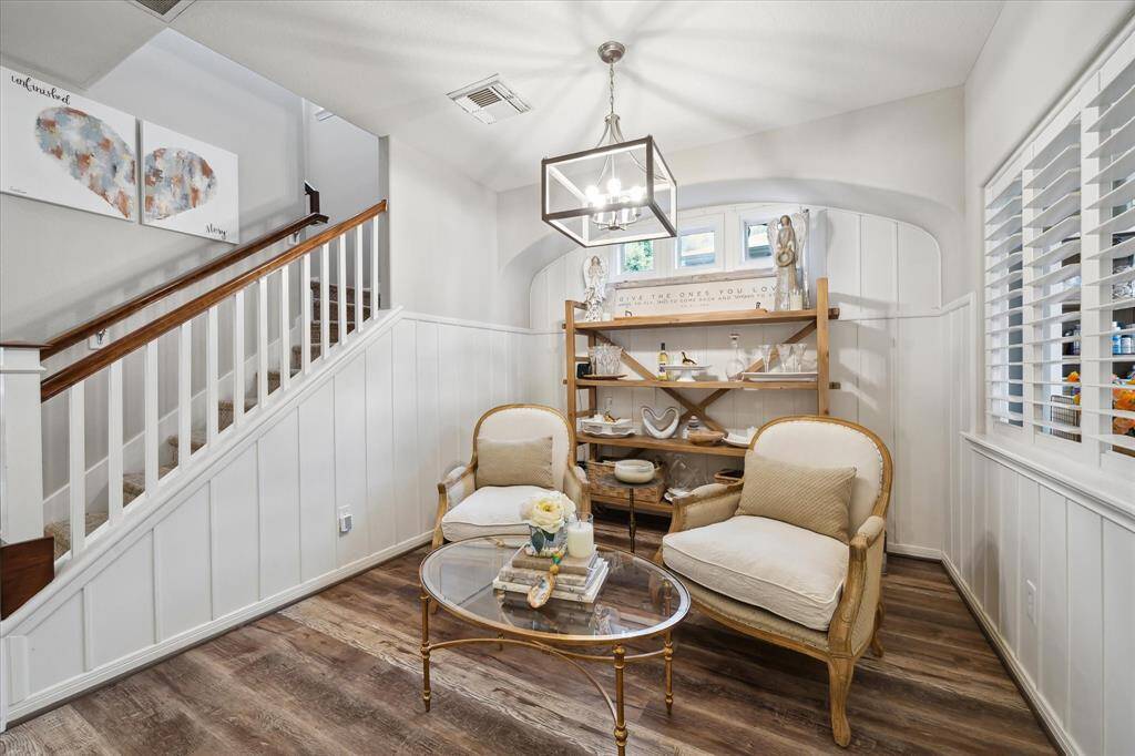Alternate view of the lounge area highlights the elegant millwork, warm wood tones, and designer lighting that enhance the space’s inviting atmosphere. Transom windows above add soft natural light, while the arched wall detail and tasteful decor elevate the charm and functionality of this cozy space.