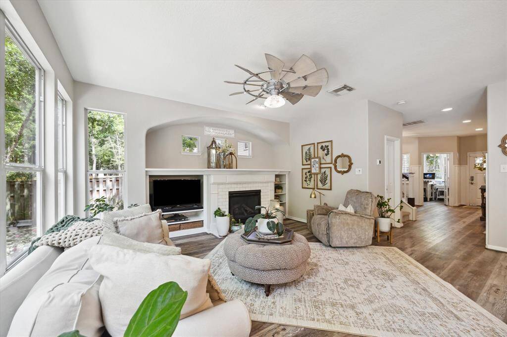 Alternate view of the living room reveals the home’s seamless flow toward the front entry, lounge area, and study. Layered textures, soft neutral tones, and continuous vinyl plank flooring enhance the open layout, while natural light and thoughtful design elements create a warm and cohesive atmosphere throughout.