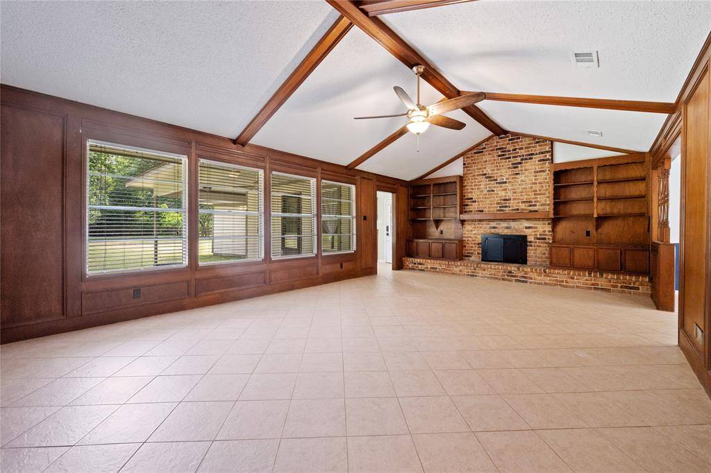 This HUGE family room has terrific personality! WOW that brick fireplace is definitely a statement piece along with the built in shelving and cabinets! Love the beams and vaulted ceilings.