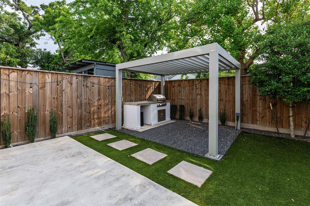 Backyard Oasis with Extended Concrete Patio, Astro Turf for No-Maintenance lawn, and Beautiful Landscaping