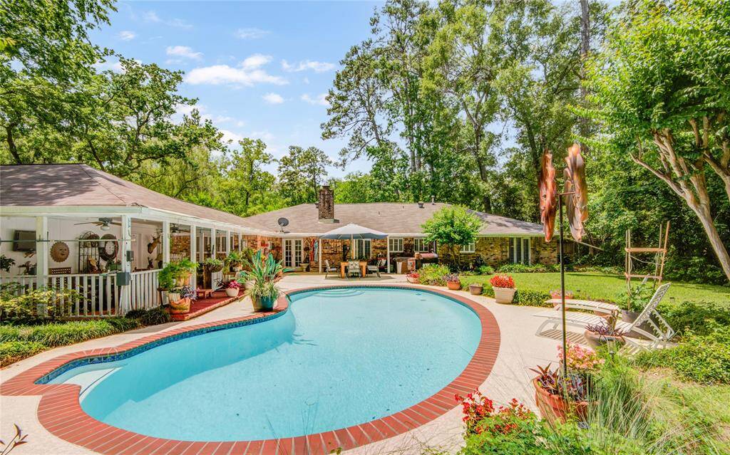 This Back Yard is an Entertainer's Paradise!!! From the far end of the pool, enjoy an open-air view back toward the home, with the expansive covered patio to the left creating a perfect outdoor living and entertaining space.