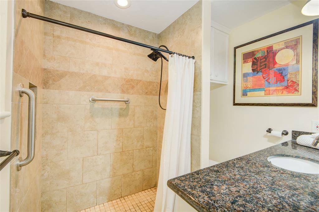 This bathroom view highlights ample cabinet storage and offers a subtle glimpse into the adjoining primary bedroom.
