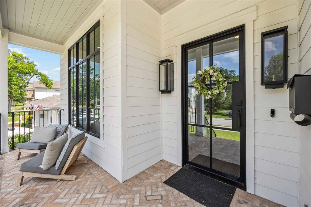 Welcome home to timeless elegance—where herringbone brick, designer lighting, and a striking glass door create a memorable first impression.