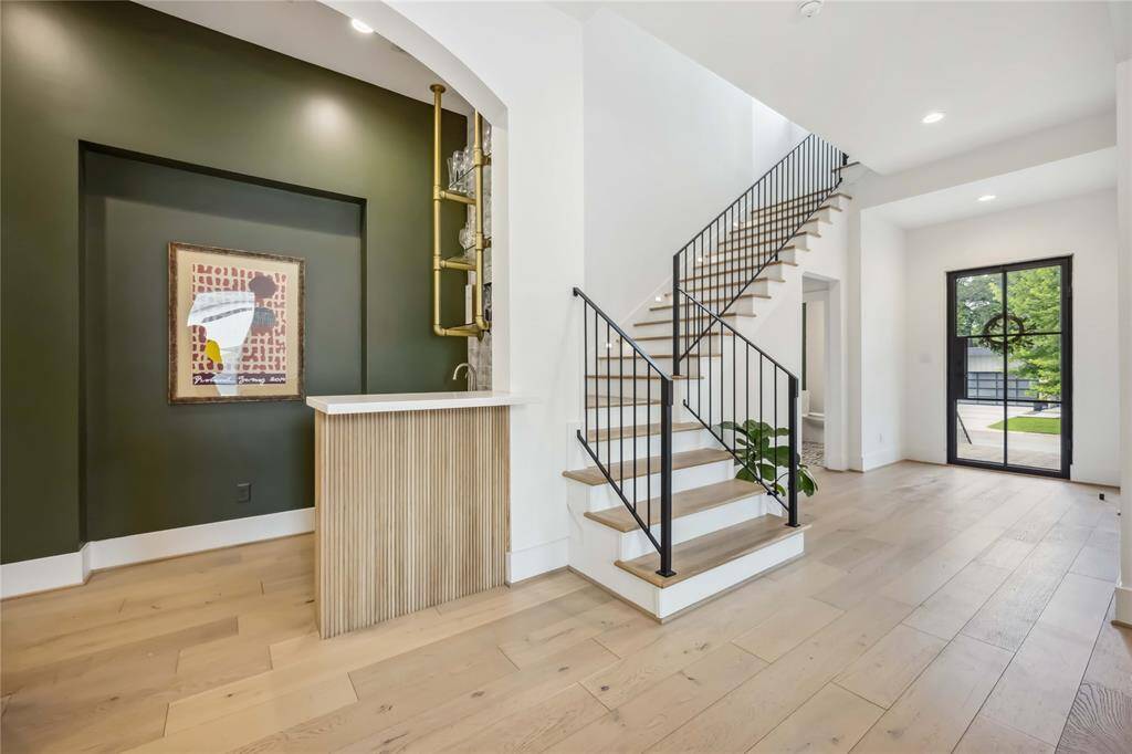 Sleek wet bar with glass shelving, ambient lighting and bar reeded paneling—perfect for entertaining in style.
