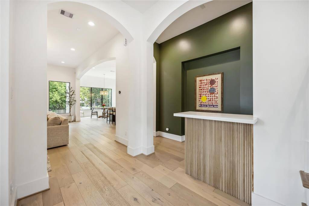 This designer family room combines warmth and sophistication with custom cabinetry, elegant library lighting, rich wood flooring, and large glass doors for effortless indoor-outdoor flow.