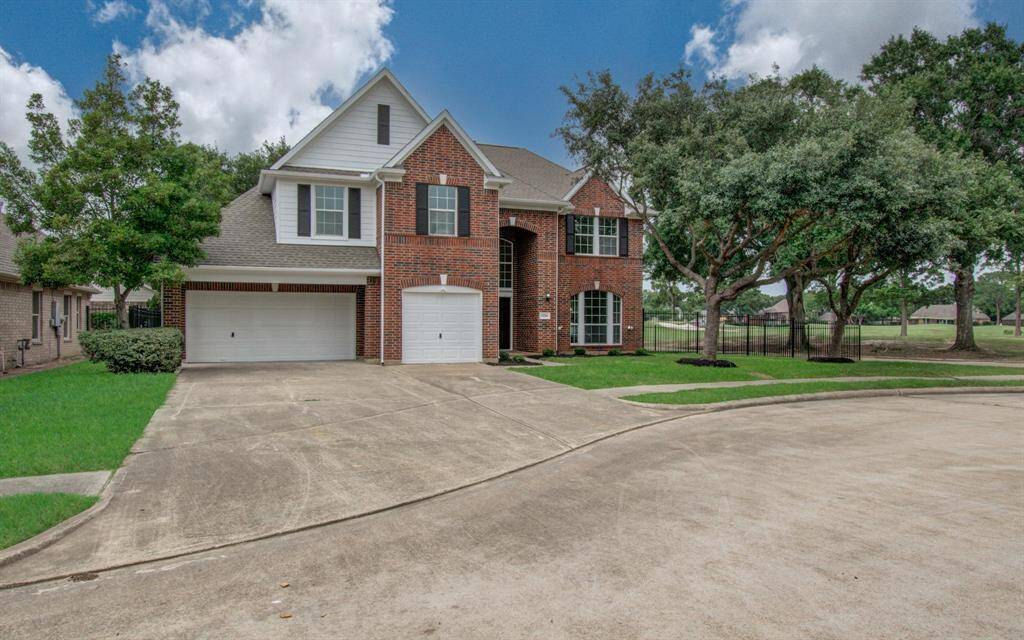 This is a two-story brick house with a classic design, featuring a spacious front yard, a two-car garage, and a prominent entrance. The home is situated on a cul-de-sac, offering privacy and a peaceful setting.