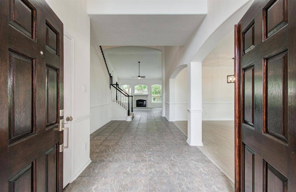 Welcome to this inviting home featuring a spacious entryway with elegant tile flooring, leading to an open living area with a fireplace. The high ceilings and large windows provide ample natural light, creating a warm and welcoming atmosphere.