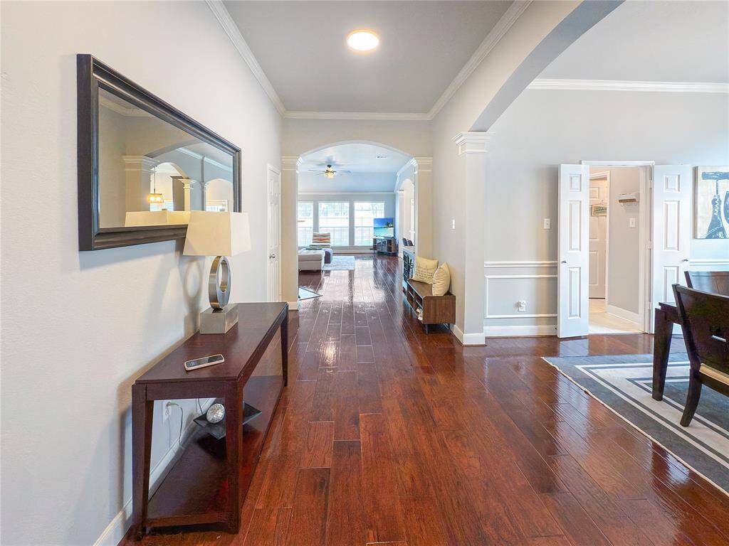This welcoming home features a bright, open hallway with elegant hardwood floors, leading to a cozy living area.