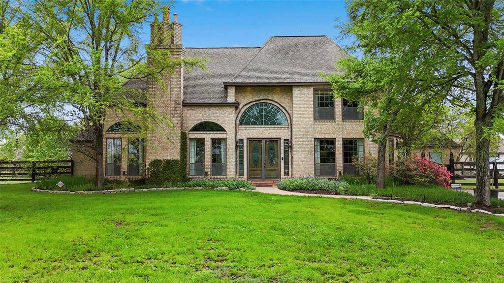Charming front view of the house featuring an elegant arched window, leaded glass double entry doors and mature shaded trees shadowing the front yard.
