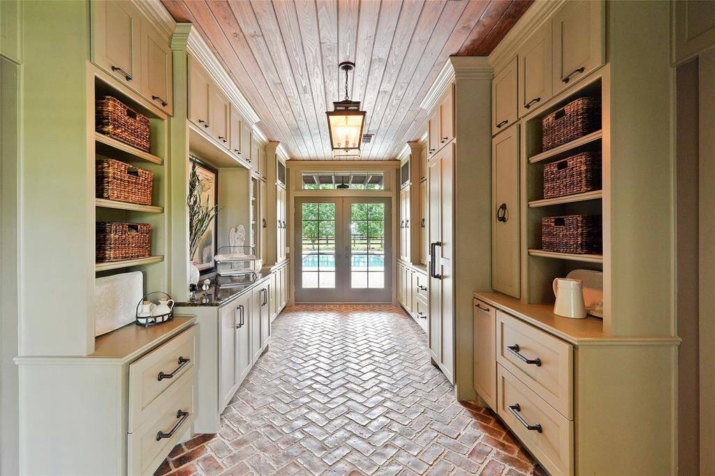 Between the family room and gym is the back entry room, featuring charming brick flooring and French doors that open to the pool.