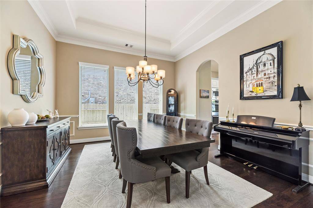 Formal dining room features a stylish chandelier, hardwood flooring, and ample natural light from the windows.