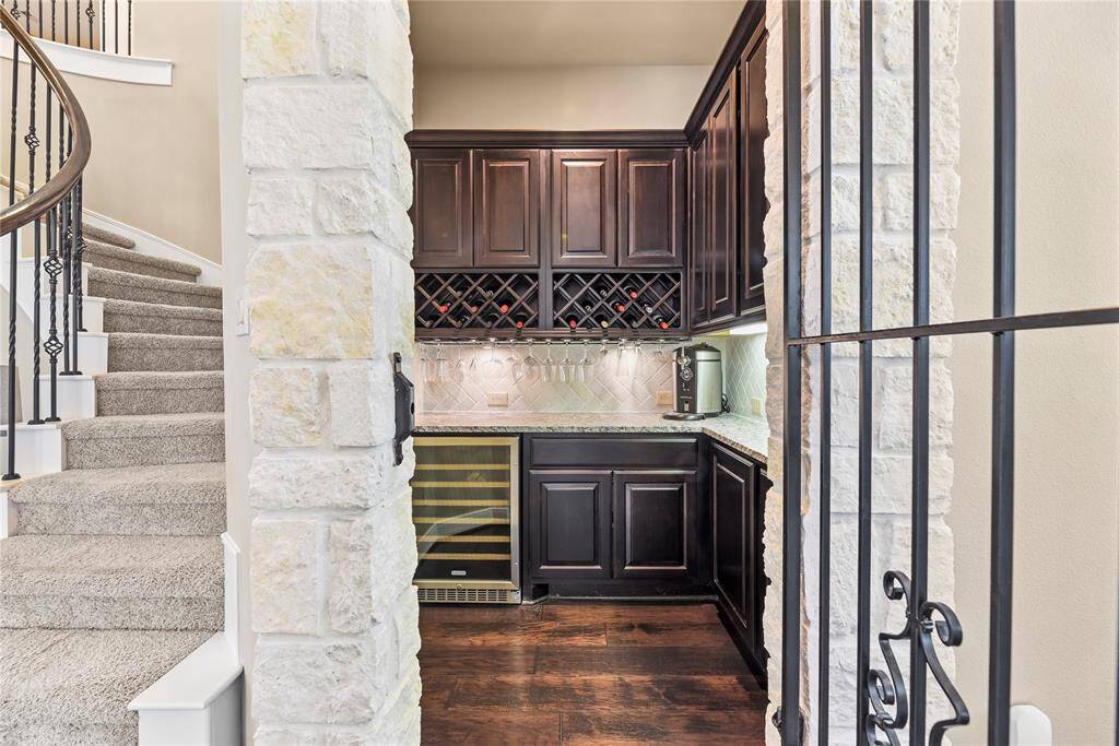 Charming bar tucked beneath the staircase, featuring rich dark wood cabinetry, a built-in wine rack, and measuring 6.3 x 6.5—perfect for entertaining with style and function.