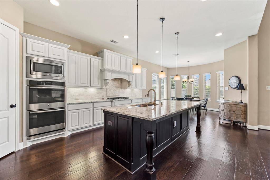 Alternate view of the kitchen seamlessly flowing into the breakfast nook, featuring large windows that offer a bright, scenic view of the backyard.