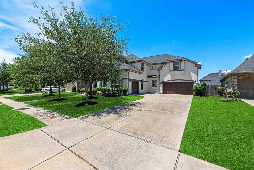 Modern two-story home with a well-maintained lawn, a spacious driveway, and a three-car garage.