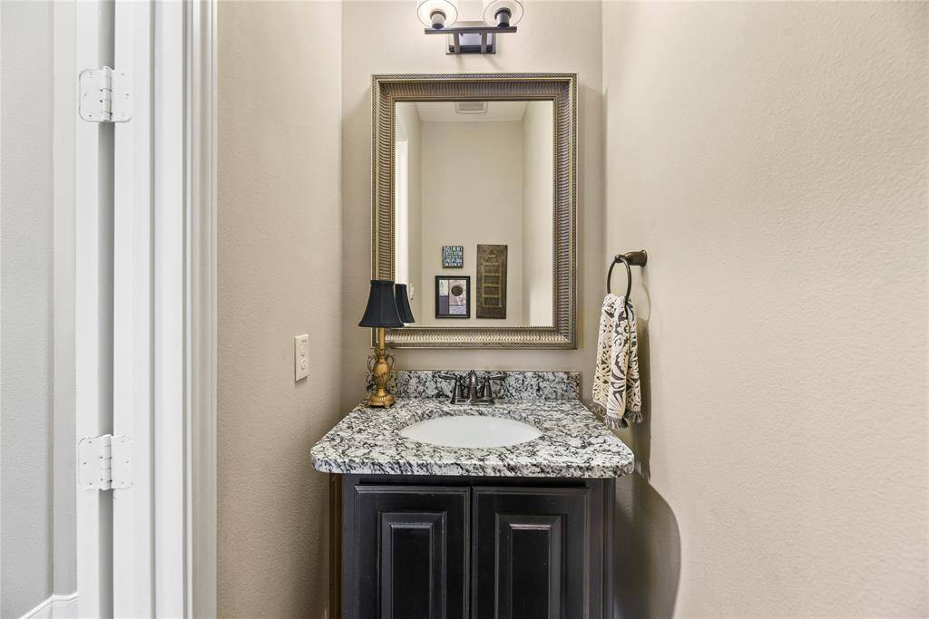 Half bathroom with a granite countertop, sink, and vanity.