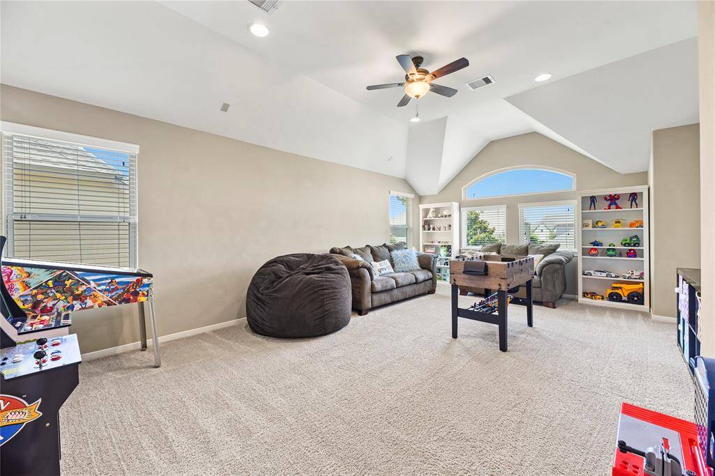 Expansive second-floor family room measuring 14.3 x 20.7, featuring a vaulted ceiling with a ceiling fan, plush carpet flooring, and large windows that fill the space with natural light.