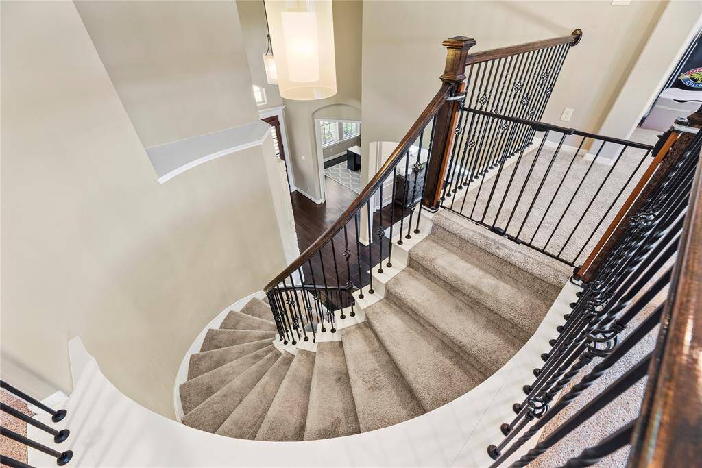 Stylish curved staircase with plush carpet, leading down to a bright, open-concept first floor.