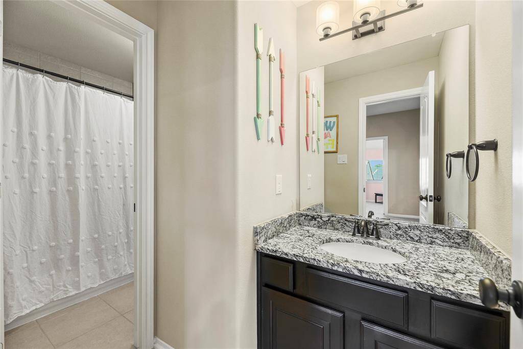 Jack-and-jill bathroom features a granite countertop with sink and vanity.