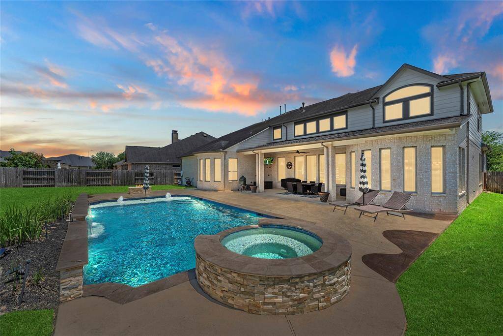 Spacious backyard with a pool and spa, surrounded by a well-maintained patio and lawn. It features a covered patio, perfect for entertaining.