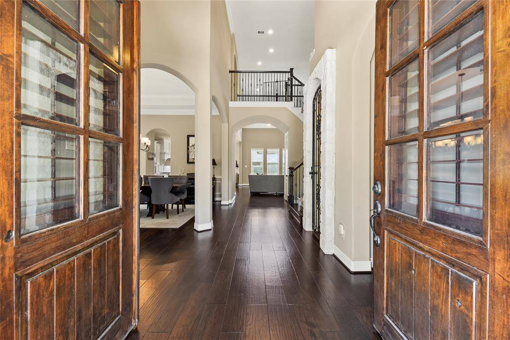 Welcome to an elegant foyer with rich hardwood floors and high ceilings. The open layout features a dining area to the left and a view extending to family room. On the left, there's a door to the home office.