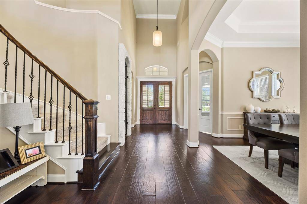 Entryway features a high ceiling and rich wood flooring, and a curved staircase.