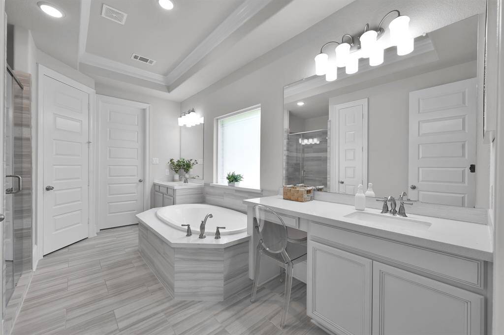 Primary bathroom features two sinks, a vanity area, soaking tub, and a walk-in Texas-sized shower with built-in bench.  Don't miss the LARGE primary closet that has a pass through to the utility room!