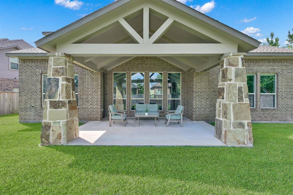 The extended covered patio, with stone columns, provides the perfect setting to enjoy the oversized lot.