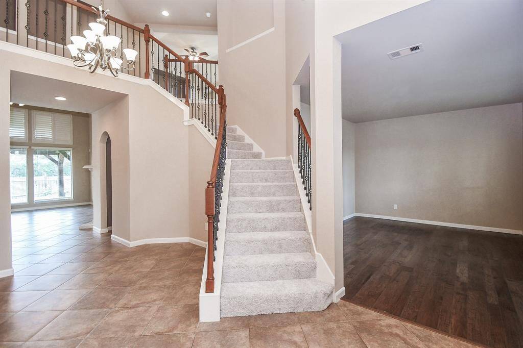 The staircase is the first thing you notice—elegant iron railings winding up like a quiet invitation to explore. Light spills in from the tall windows, and the mix of wood and tile underfoot makes it all feel grounded, warm, and just a little bit grand.