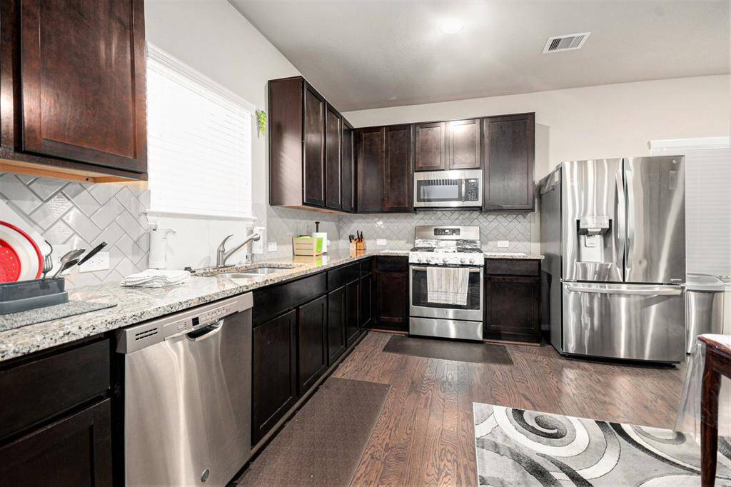 Spacious kitchen featuring sleek stainless steel appliances, elegant dark cabinetry, and beautiful granite countertops. Ideal for culinary enthusiasts.