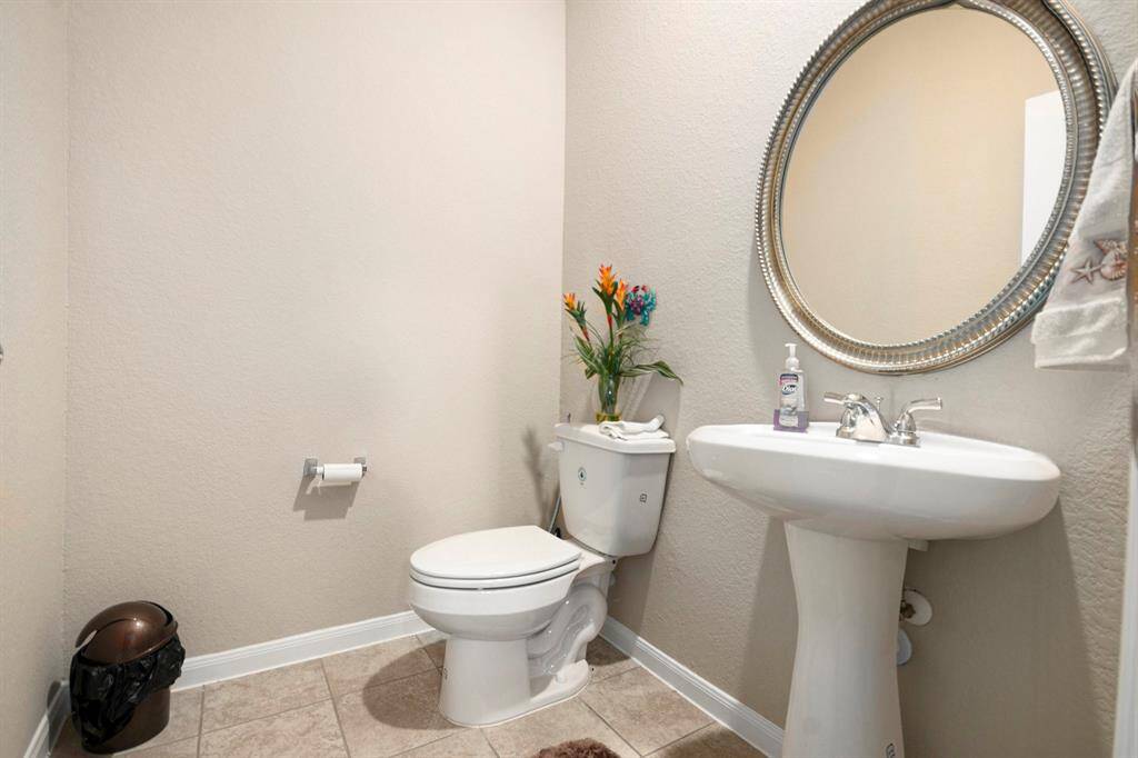 Chic half bathroom featuring a sleek pedestal sink and elegant mirror, perfect for guests.