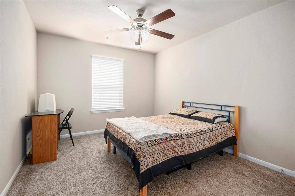 Cozy bedroom featuring soft carpeting, a modern ceiling fan, and ample natural light, perfect for relaxation.