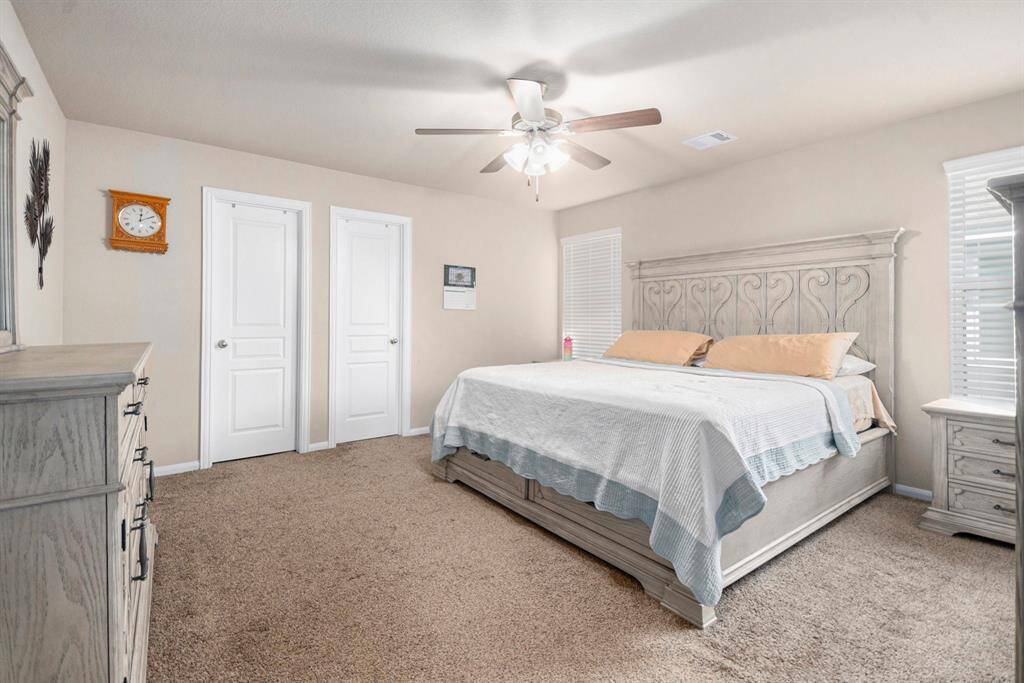 Spacious and inviting bedroom featuring soft carpeting, ample natural light, and elegant built-in storage for a serene retreat.