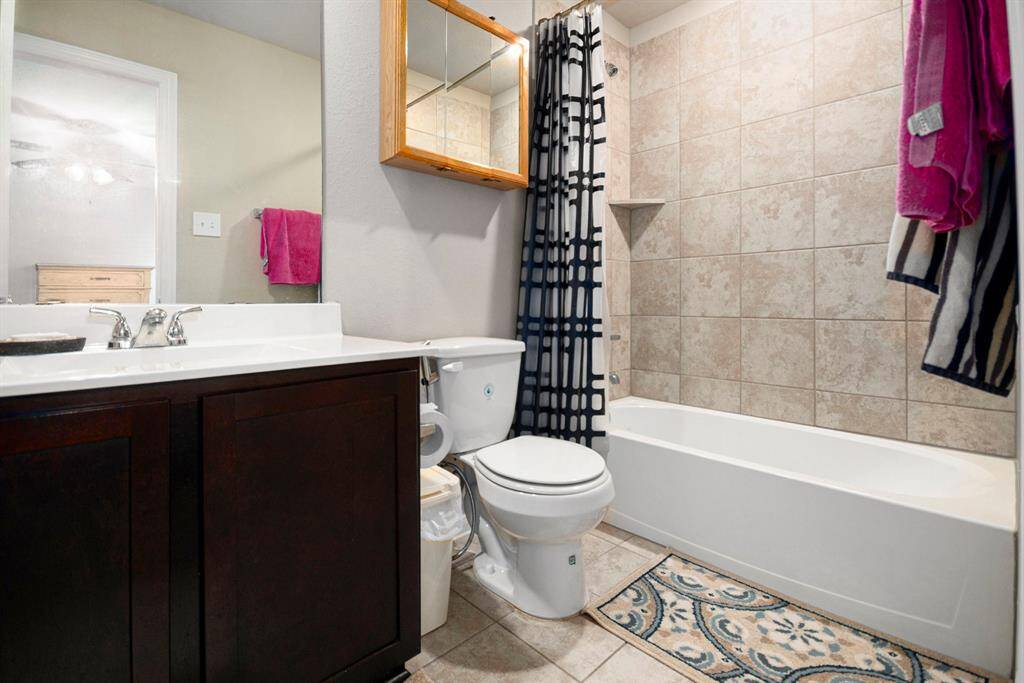 Modern bathroom featuring elegant fixtures, a spacious vanity with ample storage, and a chic tiled shower-bathtub combo. Perfect blend of style and functionality.